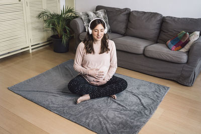 Young woman sitting on sofa at home