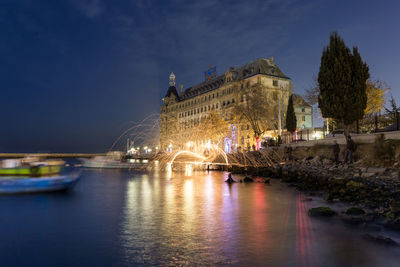 Illuminated bridge over river against sky at night