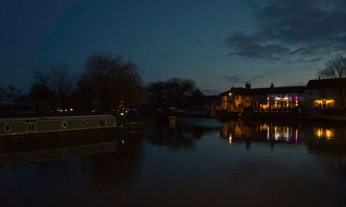 Illuminated bridge over river against sky at night