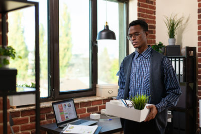 Sad businessman holding belongings at office