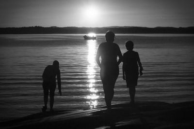 Silhouette of woman standing on beach at sunset