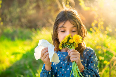 Girl with eyes closed smelling flower