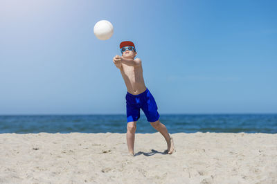 Full length of shirtless man playing on beach