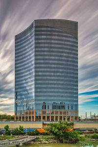 Low angle view of modern building against cloudy sky