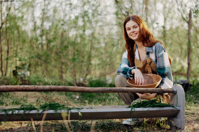 Portrait of smiling woman with food in basket at farm