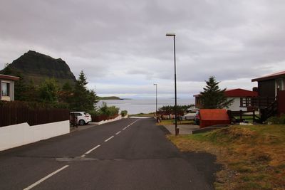 Road by buildings against sky