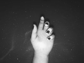 Cropped hand of woman against black background