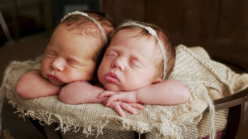 Twins sisters newborn in the winding and in a basket