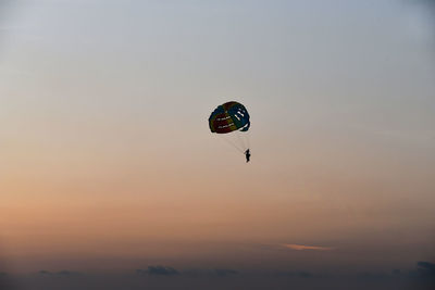 Low angle view of person paragliding against sky during sunset