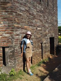 Full length of young woman standing against building