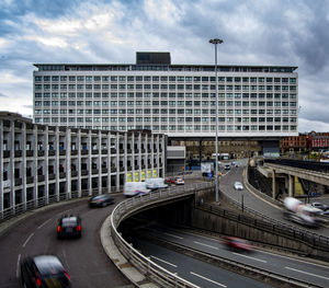 Vehicles on road amidst buildings in city against sky