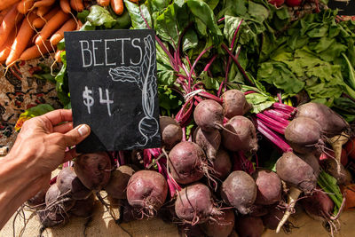 Hand holding vegetables at market stall