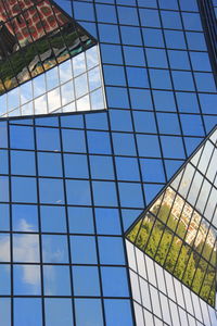 Low angle view of glass building against blue sky