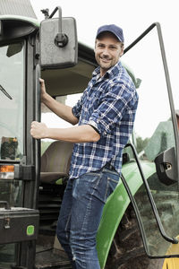 Portrait of smiling farmer entering tractor