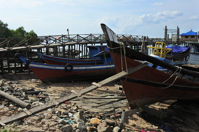 Fishing boats moored at harbor against sky