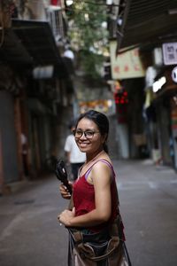 Portrait of smiling young woman standing on street in city