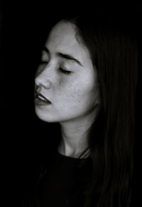 Close-up portrait of a smiling young woman against black background