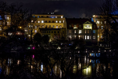 Illuminated buildings by river at night