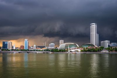 City at waterfront against cloudy sky