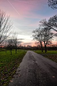 Road amidst bare trees against sky