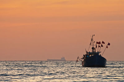 Boat on sea against sky during sunset
