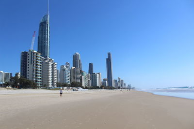 Modern buildings by sea against clear sky