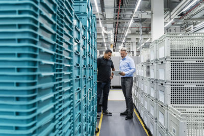 Businessman discussing with warehouse worker over tablet pc in industry