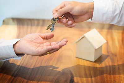 Cropped image of person giving keys to owner over table