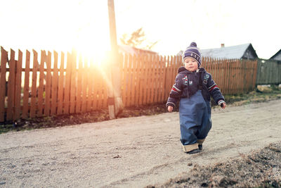 A boy in the village walks on the sand and plays with stones.