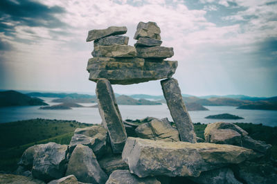 Stack of rocks at sea shore against sky