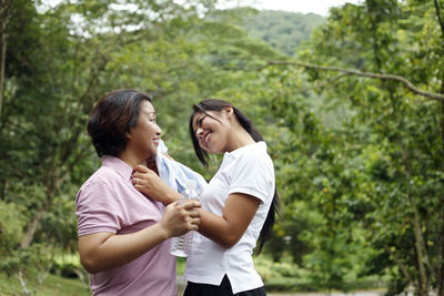 Smiling daughter wiping mother sweat after exercising