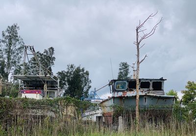 Abandoned boats in long grass against sky