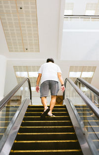 Full length rear view of man walking on staircase