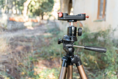 Close-up, photographic tripod with natural background out of focus. 