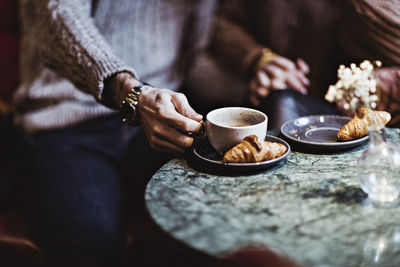 Midsection of man holding coffee while sitting with female partner in hotel