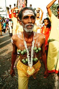 Shirtless man with garland and limes on body