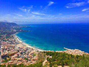 High angle view of townscape by sea against blue sky