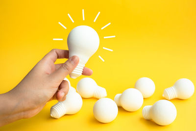 Midsection of person holding ice cream cone against yellow background