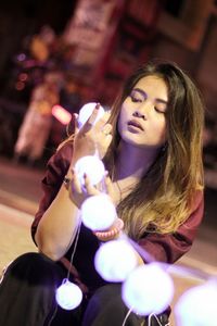 Woman holding illuminated decoration at night