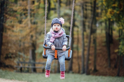 Full length of girl puckering while swinging at park