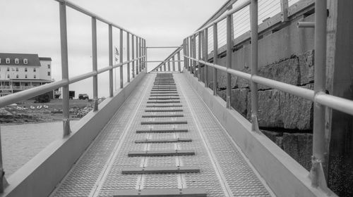 Bridge by swimming pool in city against sky