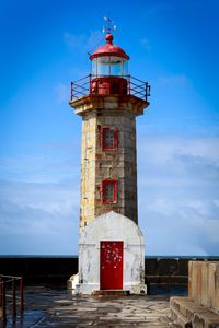 Lighthouse by building against sky