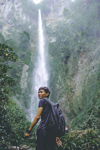 Man standing by waterfall in forest