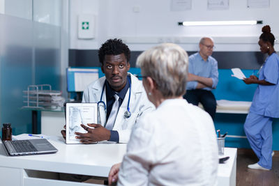 Male doctor explaining patient through digital tablet at hospital