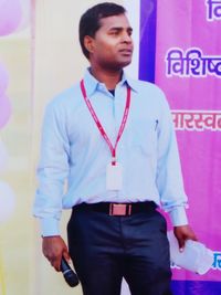 Young man looking away while standing against wall