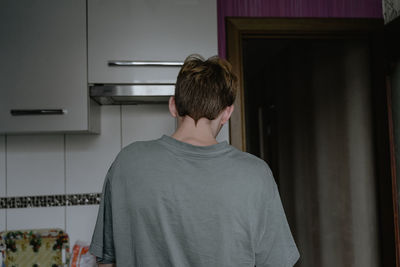 Pigtail on the back of the head, the guy is standing with his back, with a non-standard hairstyle