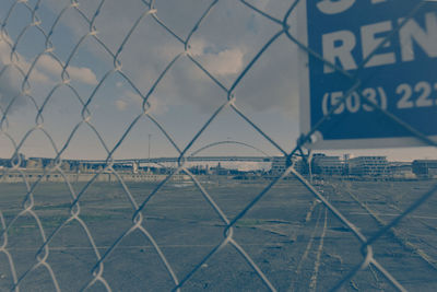 Chainlink fence against sky in city