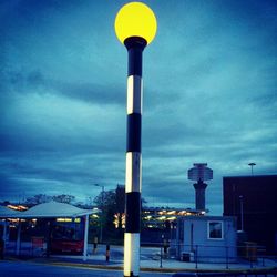 Low angle view of illuminated street light against cloudy sky