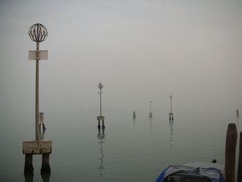 Wooden post in sea against sky