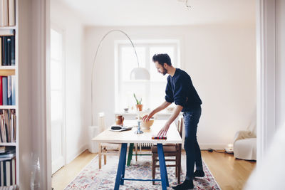 Side view of man arranging dining table at home